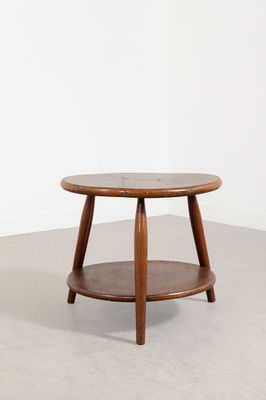une table basse ronde avec un piètement en bois dans une pièce blanche