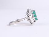 a close up of a ring with a green stone and diamonds