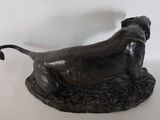bronze statue of a dog on a rock with a white background