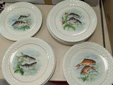 four plates with fish painted on them sit in a box