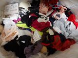 a large pile of clothing on a bed with a pair of scissors