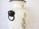 un vase blanc muni d'une anse noire posé sur une table