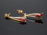 a pair of gold and ruby earrings on a black surface