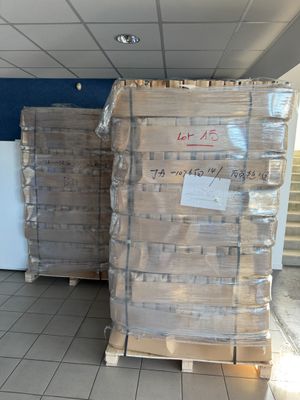 Plusieurs palettes de cartons sont empilées les unes sur les autres dans un entrepôt