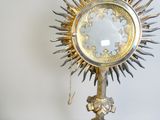 a gold and silver clock on a stand with a chain
