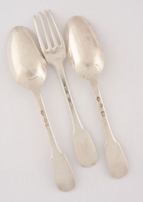 trois cuillères et une fourchette en argent sur une surface blanche