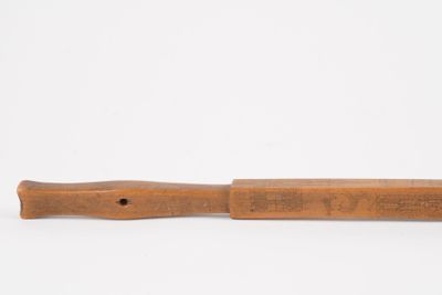 un vieux couteau en bois avec un manche en bois posé sur une surface blanche