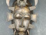 an image of a metal mask with horns and a bird on it