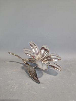 une broche en argent en forme de fleur, ornée d'une feuille