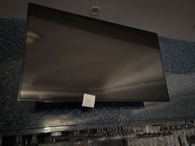 une télévision à écran plat fixée au mur au-dessus d'un casier à vin