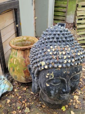a statue of a buddha head sitting next to a potted plant