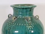 a large green vase with handles on a white surface