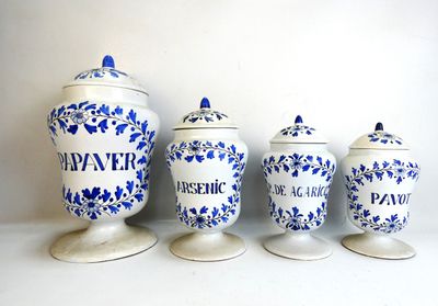 three blue and white canisters are lined up against a white wall