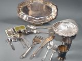 a silver plate with silverware and silver spoons on a table