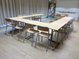 des tables et des chaises dans une salle de classe, avec un tableau noir en arrière-plan