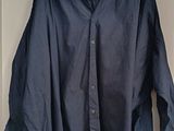 une chemise bleu marine suspendue à un cintre dans une pièce blanche