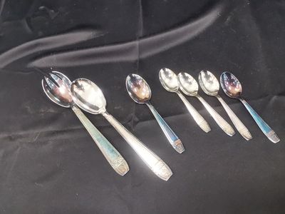 six silver spoons are lined up in a row on a black cloth