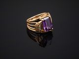 a gold ring with an amethorate stone on a black surface
