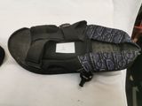 a black bag with a black strap on it and a pair of black shoes on a white surface
