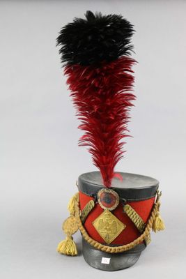 a close up of a red and black hat with feathers on it