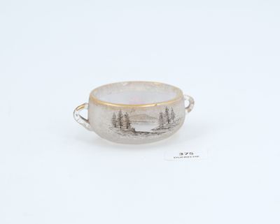 a close up of a cup on a white surface with trees in the background