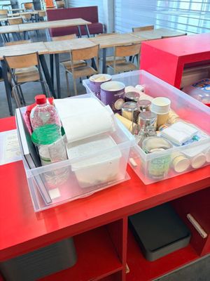 a red table with plastic containers on it in a classroom