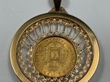 a gold coin in the center of a circular pendant on a white surface
