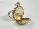 a gold pocket watch sitting on a white surface