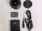 a camera, a battery, and a charger on a table
