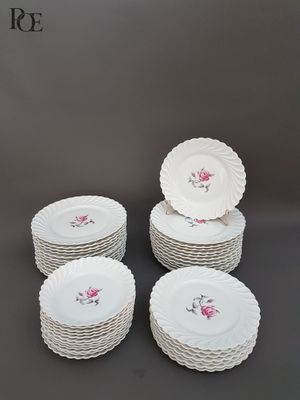 six assiettes blanches ornées de roses roses sont empilées les unes sur les autres