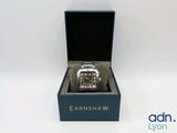 une montre posée dans un coffret sur une surface blanche