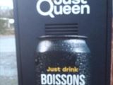 une enseigne sur le côté d'un immeuble sur laquelle on peut lire simplement « queen »