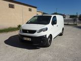 La camionnette blanche est garée sur le parking près d'un immeuble.