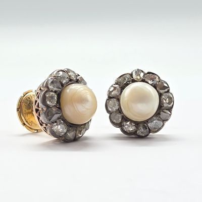 deux paires de boucles d'oreilles en perles et diamants posées sur un fond blanc