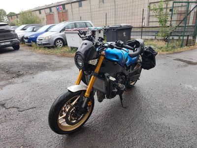 une moto bleue garée sur un parking à côté d'un immeuble