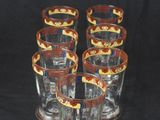 six glasses with red and yellow designs are lined up on a black background