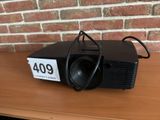 a small projector sitting on a table with a brick wall in the background