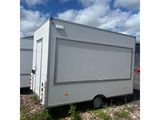 a white trailer parked in a field with a sky in the background