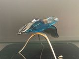 sculpture en verre représentant un oiseau posé sur un socle, sur une surface noire