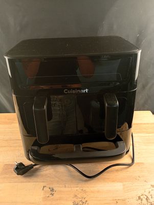 une photo d'un grille-pain noir posé sur une table en bois
