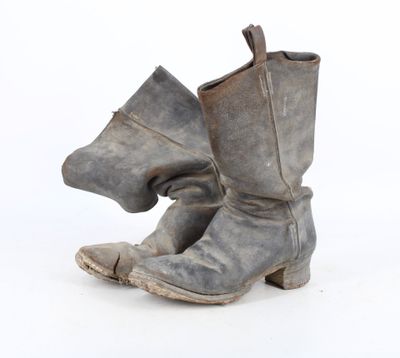 une vieille paire de bottes dont le talon est cassé, sur fond blanc