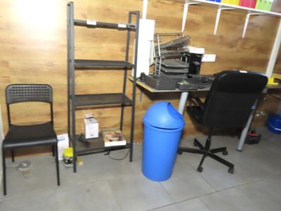 a blue trash can sitting next to a black chair in a room