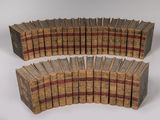 several old books are stacked on top of each other on a white surface