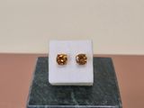 a pair of gold colored earrings on a marble block