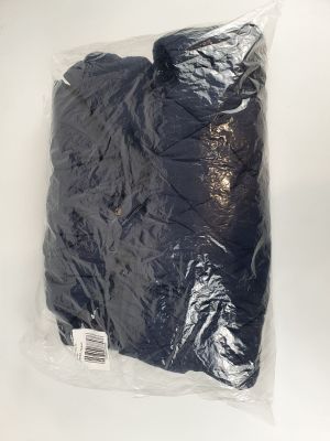 un gros plan sur un sac contenant des vêtements noirs posé sur une surface blanche