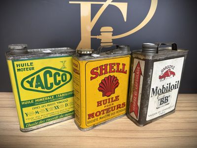 three vintage shell oil cans sitting on top of a wooden table