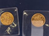 deux pièces d'or dans des étuis en plastique posées sur un fond bleu