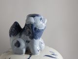 a blue and white vase with a small figurine on top of it