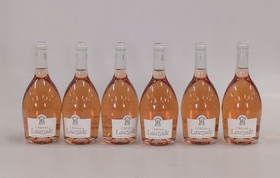 six bouteilles de vin rosé alignées sur une surface blanche