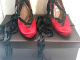 une paire de chaussures à talons hauts rouges et noires, posée sur une boîte noire